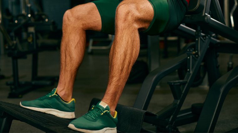 legs of person in gym squatting on machine